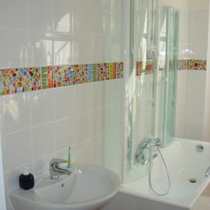 Décor de salle de bain en mosaïque au motif coloré en translucides, faïence et cabochons de verre Albertini